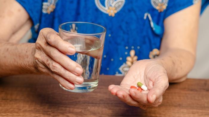 La toma diaria de un suplemento multivitamínico frena levemente el envejecimiento biológico, según un ensayo clínico Mujer mayor toma pastillas con un vaso de agua.